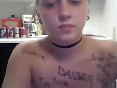 Ponytailed blonde girl writes all kinds of words on her naked body in the kitchen